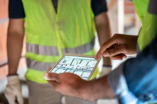 مهندس خدمات هندسية معتمد يراجع مخطط البناء في موقع المشروع لضمان الجودة والدقة