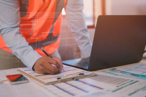 مهندس يراجع تقرير فني لمشروع هندسي على موقع البناء، لضمان مطابقة المواصفات السعودية والمعايير المعتمدة.